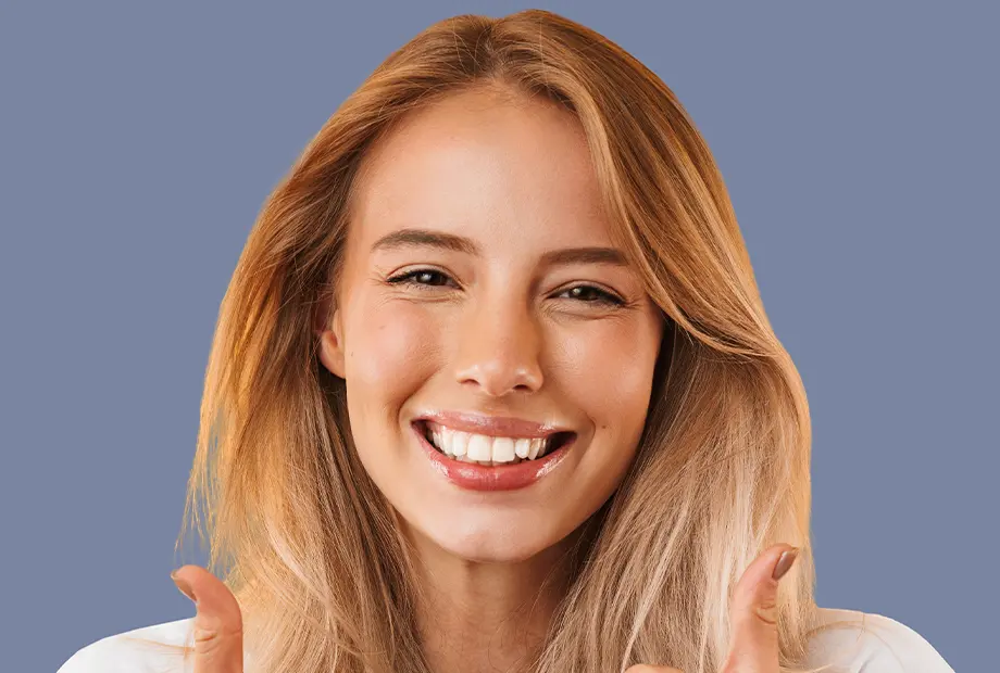 Zahnaufhellung blankweiss - glückliche Patientin zeigt beide Daumen nach oben